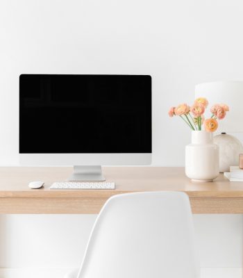 iMac on wooden desk with orange flowers in a white vase