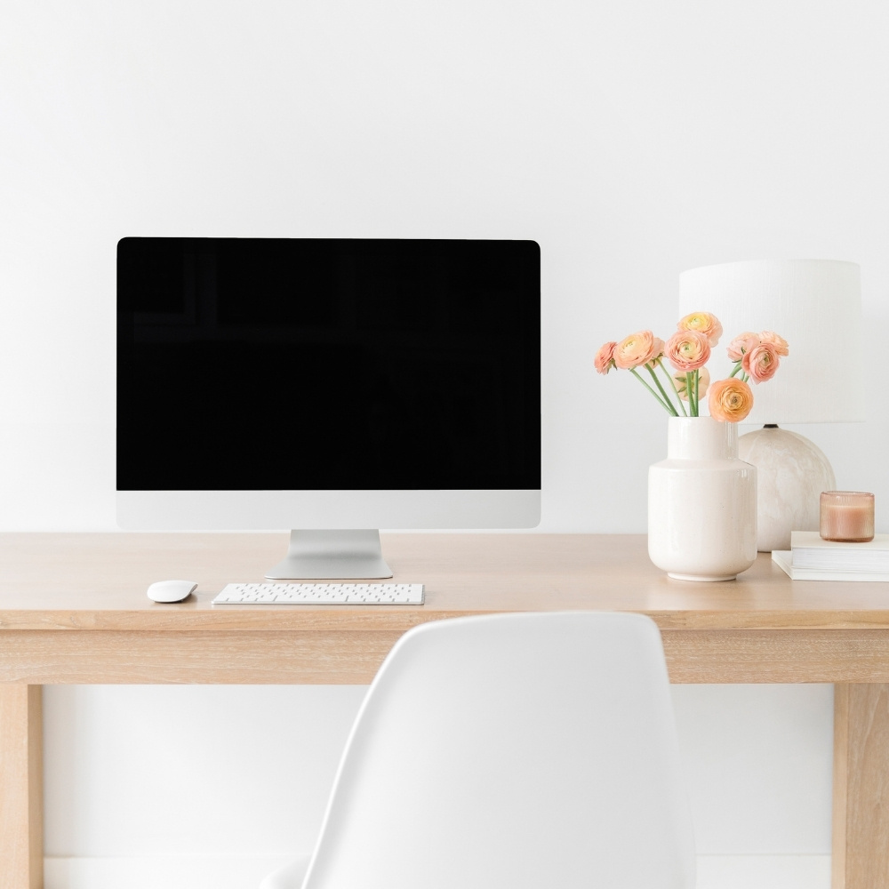 iMac on wooden desk with orange flowers in a white vase