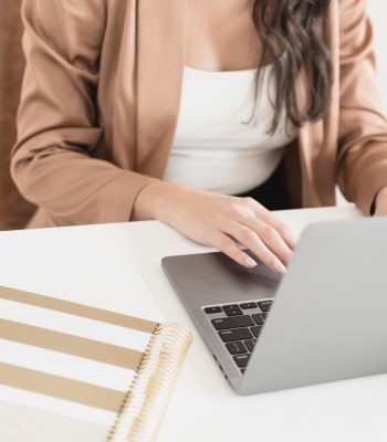lady with brown blazer sitting at desk with laptop