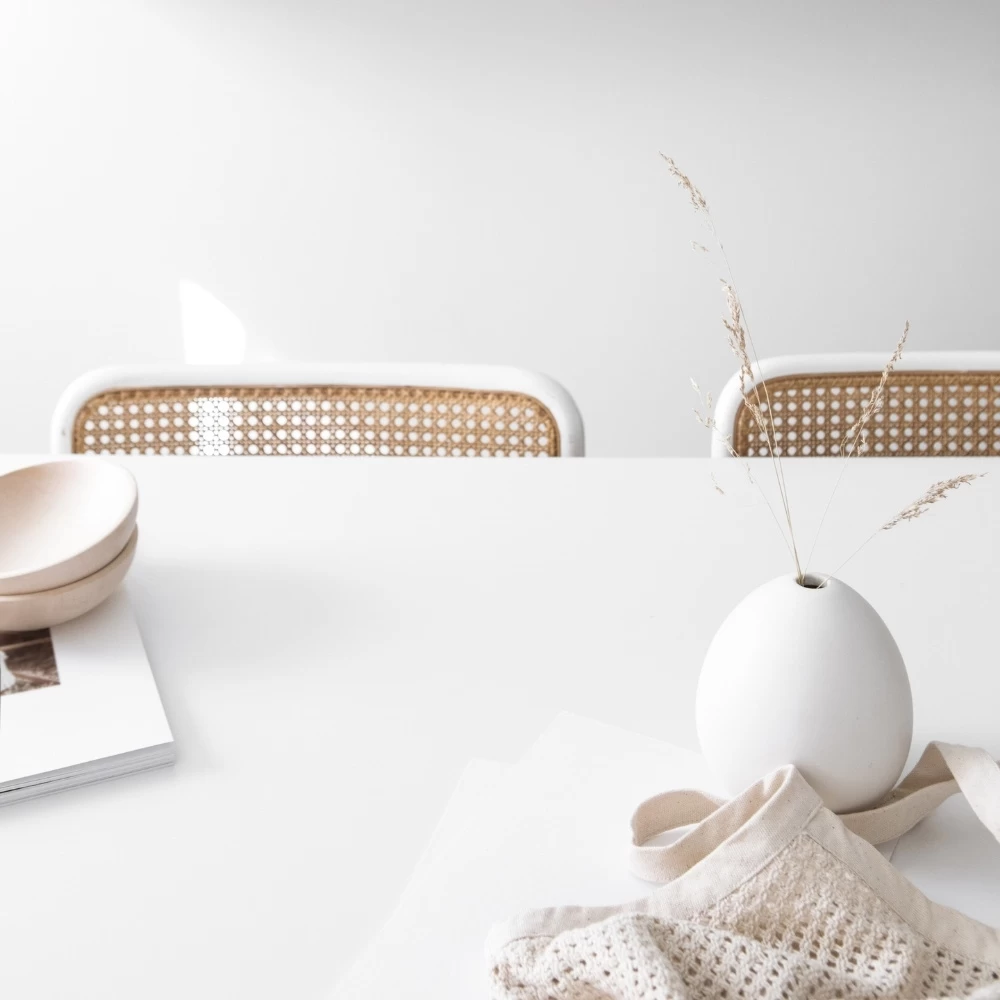 table with wicker chairs and vase of dried leaves