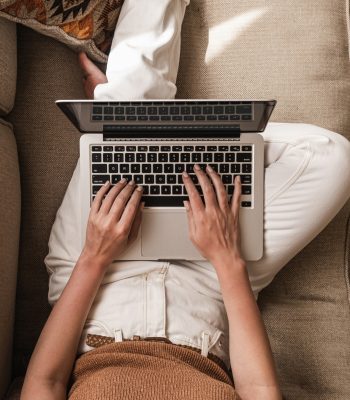 female blogger laying on couch typing on laptop