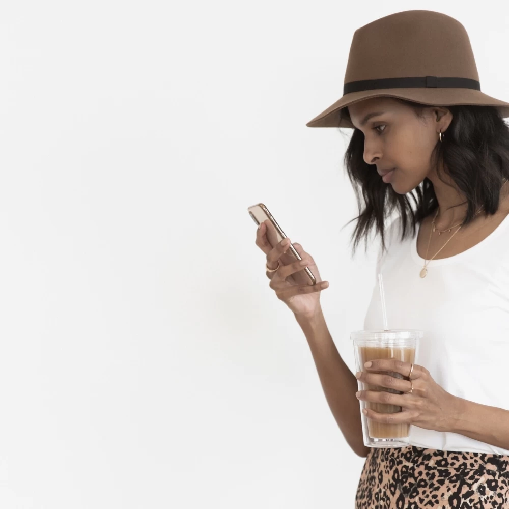 why preview planner might be the best scheduler for you 1 female blogger with white shirt and leopard dress holding phone and ice coffee